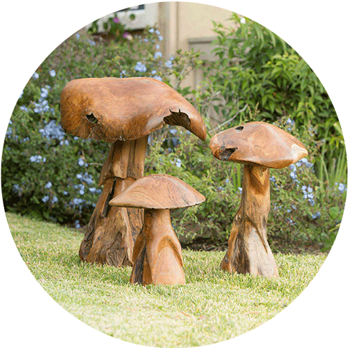 Three wooden mushroom garden art statues in a lawn and garden area.